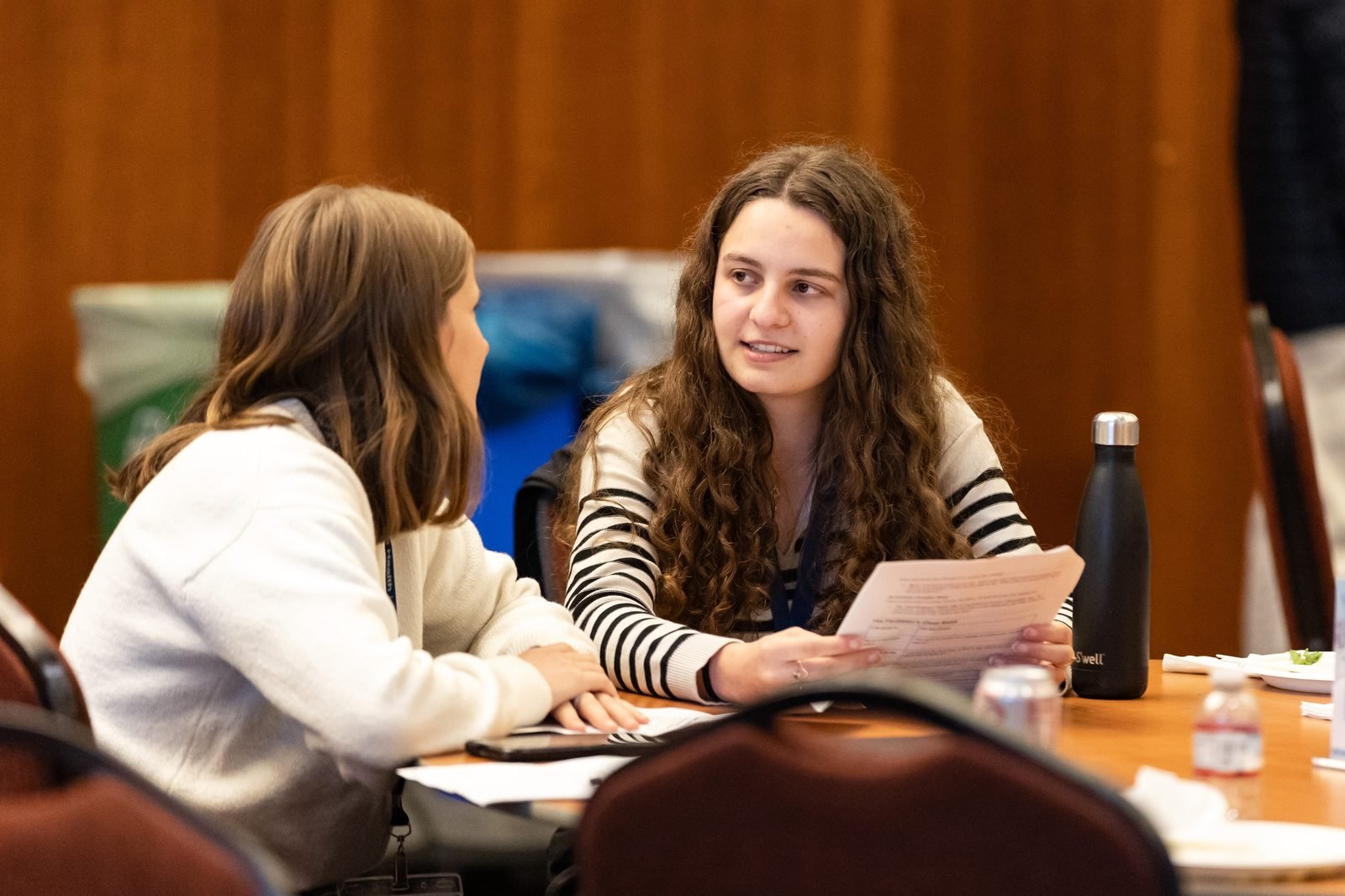 Two attendees discussing a proposal over paperwork at a table