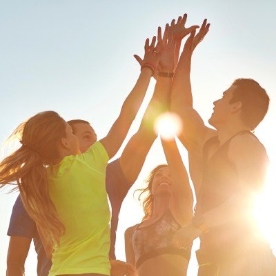 Group of friends high-fiving outdoors in the sun